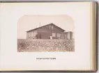 Vy över expeditionens vinterkvarter Polhem i Mosselbukten på Spetsbergen, uppfört under den Spetsbergsexpeditionen 18721873 under ledning av Adolf Erik Nordenskiöld. På bilden syns två expeditionsmedlemmar och tre hundar framför trähuset.