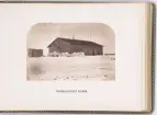 Vy över expeditionens vinterkvarter Polhem i Mosselbukten på Spetsbergen, uppfört under den Spetsbergsexpeditionen 18721873 under ledning av Adolf Erik Nordenskiöld. På bilden syns två expeditionsmedlemmar framför trähuset.