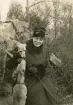 Porträtt av en kvinna med två hundar som sitter ute i naturen.