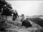 Man och kvinna sitter på klippan vid vattnet, Uppland
