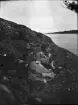 Inez Hällbom halvligger på klippan vid vattnet, Uppland