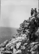 Män och kvinnor går ner från en klippa vid vattnet, Gotland