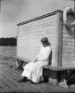 Flicka sitter på en bänk på bryggan, Norsborg, Södermanland