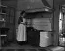Kvinna står vid vedspis, Uppland