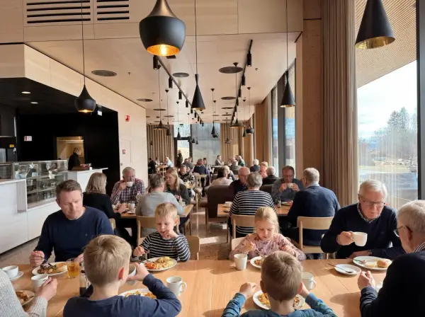 Familier med barn sitter ved bord og spiser i en moderne kafé på Anno Domkirkeodden historiesenter.
