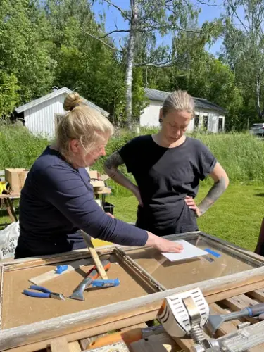 två personer renoverar ett fönster
