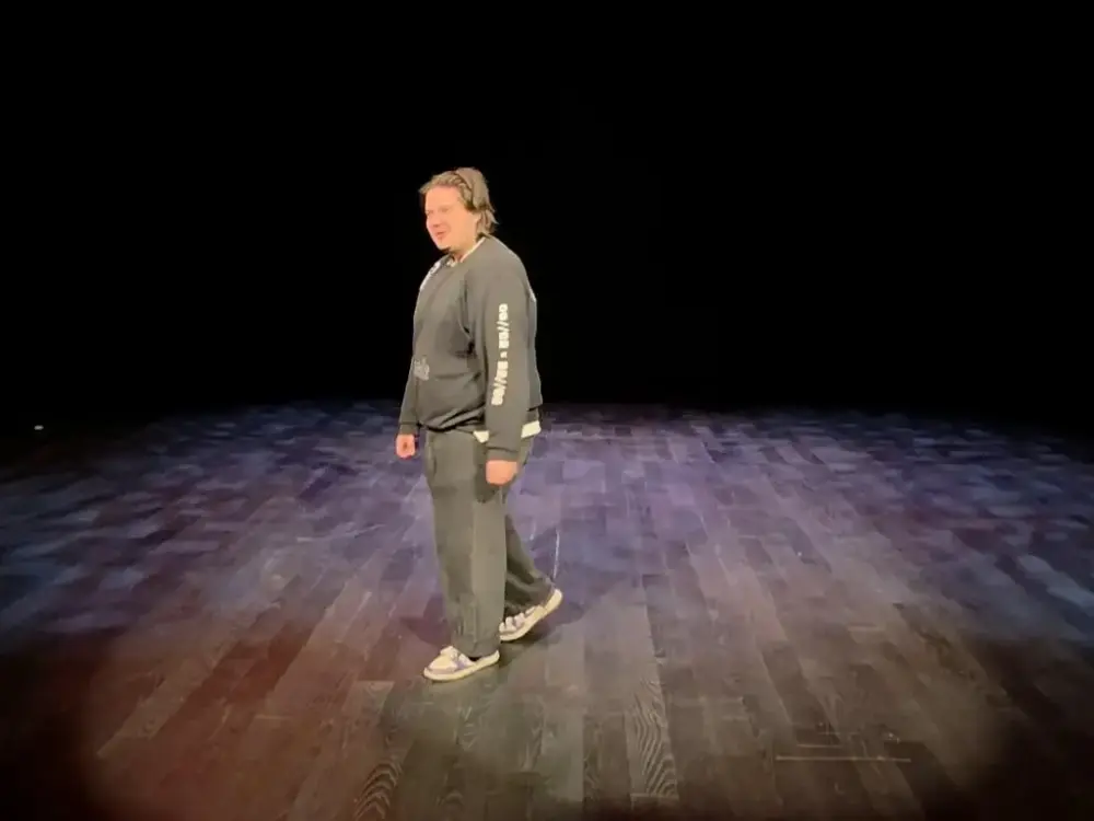 En mann står alene på scenen. 