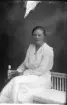 Porträtt av okänd ung kvinna i ljus klänning, hon sitter på en soffa i gustaviansk stil.