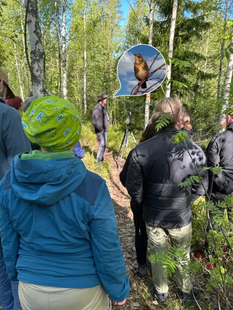 Flera personer som står i en skog och en infälld fågel.
