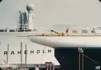 Yawlen Hazard III står lastad på en tångvagn på kajen framför Svenska Amerika Liniens lastmotorfartyg BRAHEHOLM. Snart ska hon lastas på fartyget för att transporteras till USA, där hon ska delta i Newport-Bermuda race.