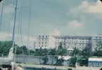 The Bermudiana Hotel sedd från vattnet i Hamilton Harbour med en segelbåtsmast i förgrunden.