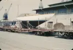 HAZARD III ligger lastad på en tågvagn i Göteborgs hamn i väntan på att lyftas ombord på Svenska Amerika Liniens lastmotorfartyg BRAHEHOLM, med vilken hon ska fraktas till Boston Harbor för att delta i Newport Bermuda Race.