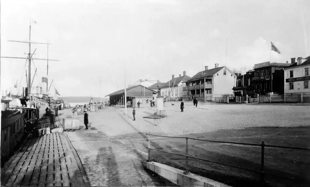 Svartvit foto med vy från Nybron. Skepp och människor vid hamnen.