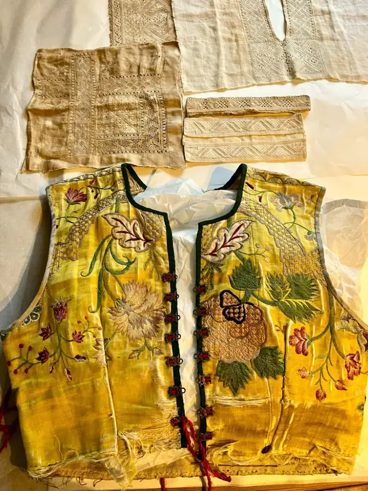 Bilde av en gul brodert vest, i bakkant hvitsomsbroderi