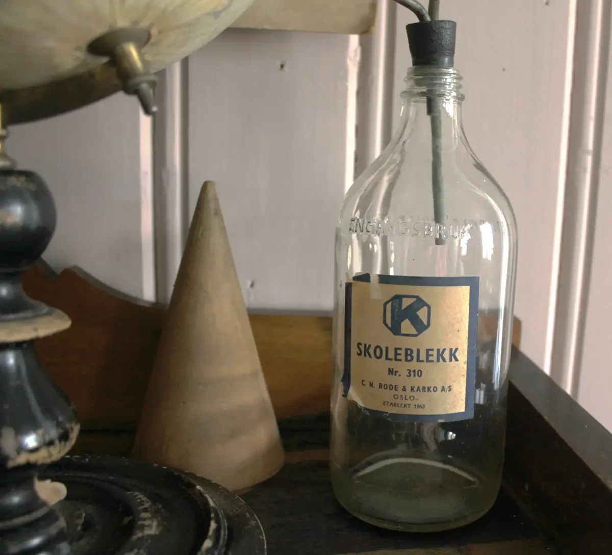 Glassflaske med papiretikett og teksten "skoleblekk". 