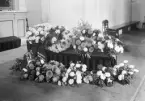 Begravning med kista och blommor i kyrkan.