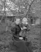 Anna Andersdotter med sonen Ernst hemma på gården Norra Bråta i Svinhult. Här avbildade omkring år 1900. Oaktat den synbara idyllen rymmer porträttet tragik. Anna sägs blivit illa behandlad av sin man och äktenskapet upplöstes efter utslag i Domkapitlet i Linköping 1902. Efter en tid hos sin bror i Lilla Bona avled hon redan 1905 i sviterna av epilepsi. Sonen Ernst fick lyckligtvis ett långt liv och kom under större delen att arbeta som vägarbetare i Svinhult.