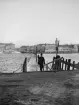 Flottbroar var i äldre tider en använd lösning i Stockholm. Här bron över Riddarfjärden som trots sin provisoriska karaktär var utrustad med ljuslyktor. I bakgrunden fyller Gamla stans siluett större delen av fonden. Foto omkring år 1900.