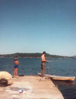 En gutt og en mann står på en brygge. 