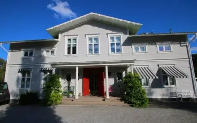 Ett hus med röd dörr med två buskar vid framsidan.