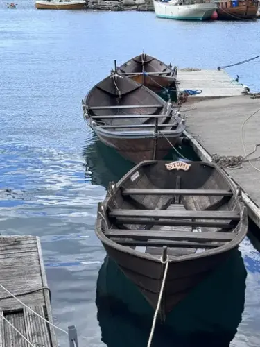 tre robåter ligger ved en flytebrygge, alle båtene er trebåter og to av dem er oselvere