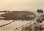 Vältplats i Linghed (enligt text i album). Slänten är klädd med timmer så att det lossade timret lättare skall rulla ned i vattnet. Till höger i bild syns stationshuset. (Källa: historiskt.nu)