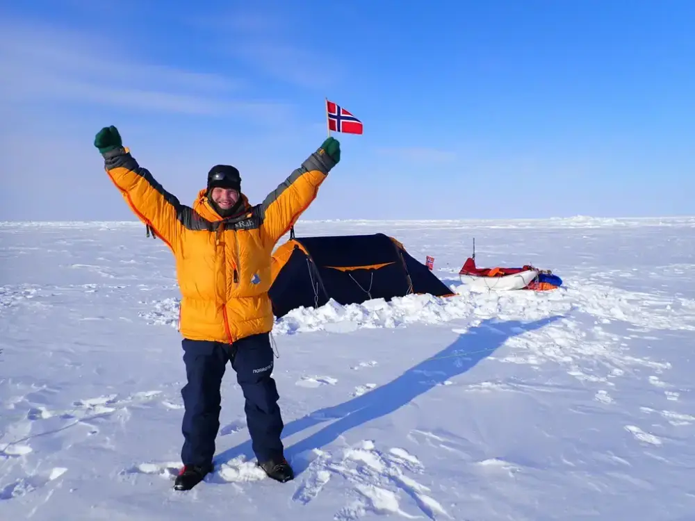 Anders Brenna ikledd tykke vinterklær og med flagg i hånda. I et isøde