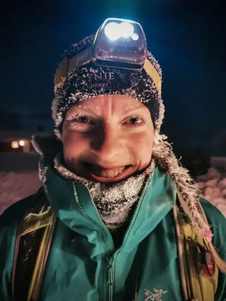 Portrett av Gina Johansen med snø og is i håret - lue og hodelykt 