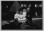 Gruppbild troligen av hela familjen Klaus sittandes på stenar i skogen framför två tält.

Enligt bilaga, 