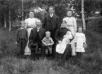 Johannes Andersson och hustrun Karolina Samuelsdotter omvärvda av sin barnaskara. Paret hade en längre tid varit hemmansägare i Svinhult och sedan hösten 1897 ägde de ett kvarts hemman i Idhult. Bilden kan utifrån sonen Gunnar i moderns knä dateras till 1907. Övriga barn ses stående från vänster i äldsta dottern Hanna Karolina, äldste sonen Johan Oskar Albrekt och Jenny Sofia. I främre radens barn från vänster står Gustaf Arvid Elmer, Karl Erik Georg, nämnda Gunnar och Karin Elin Maria.