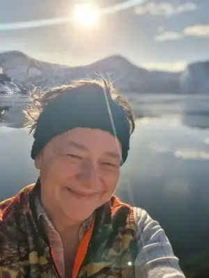 Portrett av Løvik med pannebånd foran sol, fjell og hav