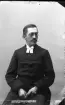 Porträtt av en okänd ung präst med mustasch och glasögon.