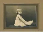 Ett fotgrafi taget i en fotostudio på ett barn som sitter omvirrad med tyg.