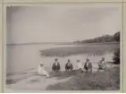 Fotografi över ett mindre sällskap sittandes på en stenklippa vid ett större vattendrag.
