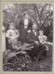 Familjefoto över två barn och två vuxna i en trädgård.