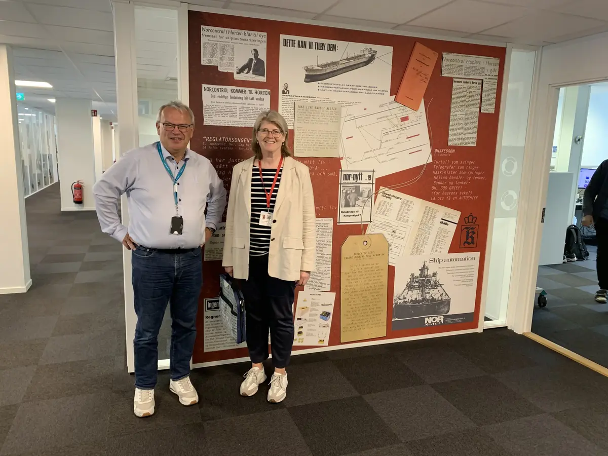 Mann og kvinne foran infotavle hos Kongsberg Maritime