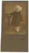 Porträtt föreställande Sigge 1 1/2 år 1919 som står lutad på en stol iklädd vinterkläder.