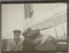 Män vid mast ombord ett segelfartyg med beslaget segel.
