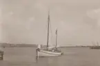 Segelskuta med beslagna segel på väg mot kaj.