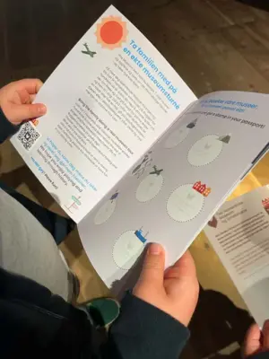 Vi ser barnehender som holder et oppslått barnas pass aktivitetshefte