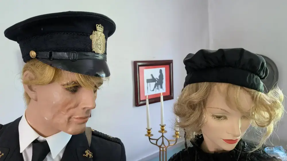 Bilde av to hoder av utstillingsdukker. En mann og en dame. Han ser på henne og hun ser bort. Han er i uniformslue. Hun har hodeplagg