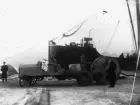 Lastbil, kabelbil, tillverkad för Telegrafverket vid Söderbloms Gjuteri AB i Eskilstuna omkring 1903-1906. Bakom skymtar förstäven av fartyget Alexandra. Fotografiet är taget på Skeppsbron.
