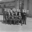 Grupporträtt av manskap och marinofficerare poserande framför kasernbyggnad vid Stockholms örlogsstation.