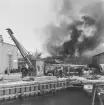 Brand i interimsörrådet på Stockholms örlogsvarv. En folksamling iakttar brandkårens släckningsarbete.