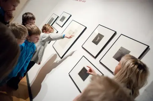 Barn ser på fotografier i en museumsutstilling
