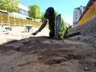 En arkeolog arbetar med framrensningen av en stenpackning vid en arkeologisk undersökning vid Juneporten i centrala Jönköping.