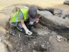 En arkeolog visar upp bronsbitar hittade med metalldetektor vid en arkeologisk undersökning vid Juneporten i centrala Jönköping.