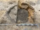 En större grop, halverad med ett undre lager framrensat. Gropen framkom vid en arkeologisk undersökning vid Juneporten i centrala Jönköping.