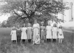 Svinhults skola läsåret 1920-21. Samlade invid kyrkan står från vänster Gerda Johansson i Idhult, Gullan Halldén i Stenstugan, Nanny Jonsson i Råås, Linnéa Liedbergius i Svinhult, lärarinnan Sigrid André, Margit Johansson i Norra Bråta, Märta Jonsson i Råås, Iris Andersson i Mostugan och Gerda Samuelsson i Klockarp. Sittande Georg Stridh i Björkliden.