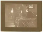 Interiörfoto av en man och en fru sittandes vid ett bord. Carl Ramström med fru född av Klintberg.